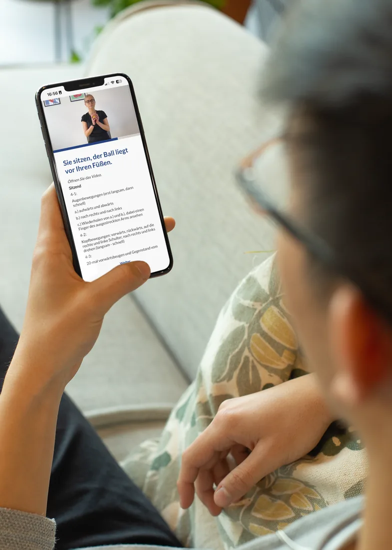 Ältere Patientin entspannt auf dem Sofa mit dem Smartphone